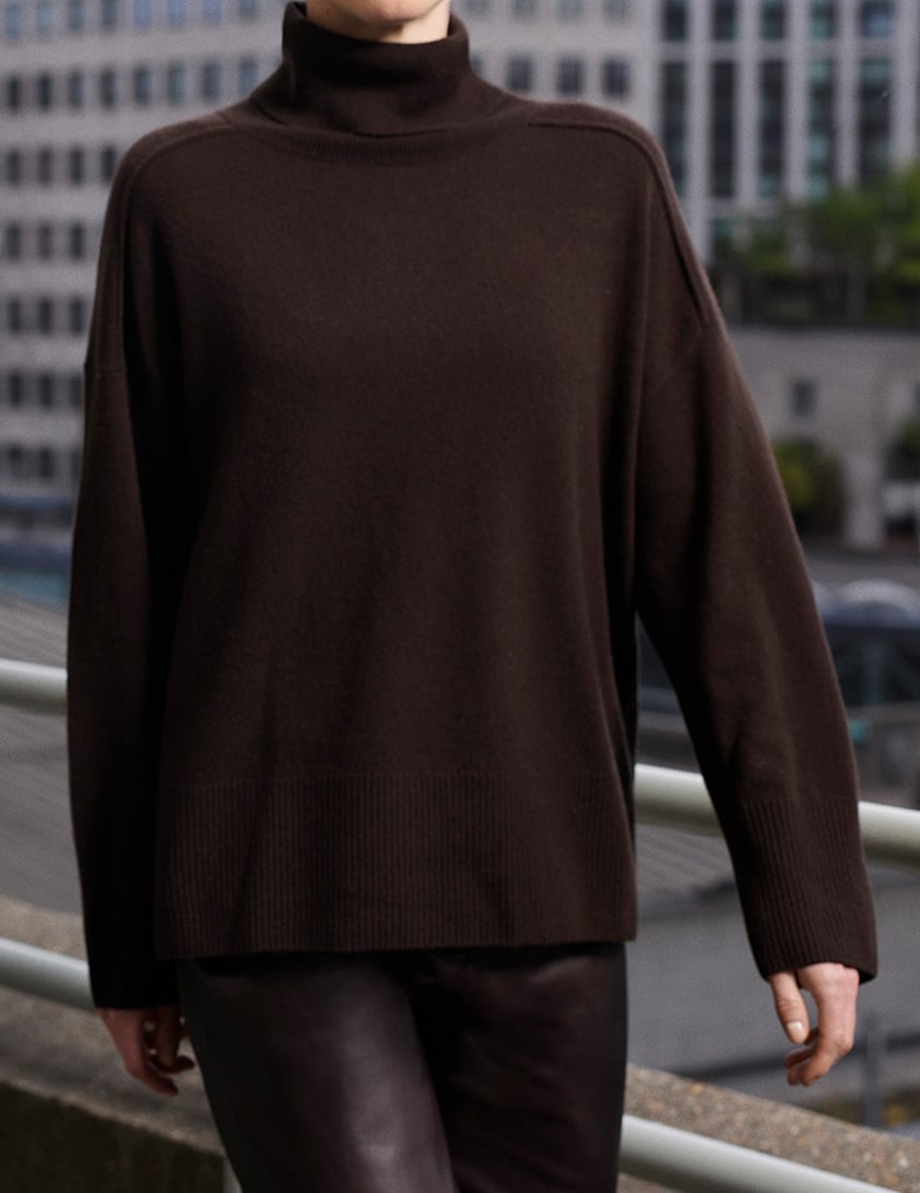 Model wearing dark brown cashmere turtleneck sweater from Whistles, styled with leather trousers