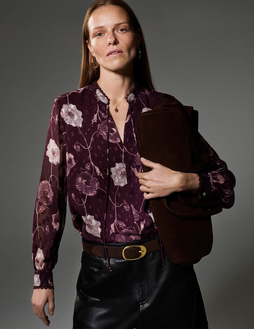 Model wearing Whistles sheer floral blouse in deep plum with black leather skirt and suede belt