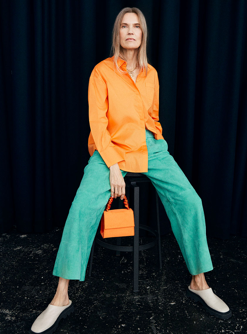 womans sitting wearing a orange shirt and green trousers