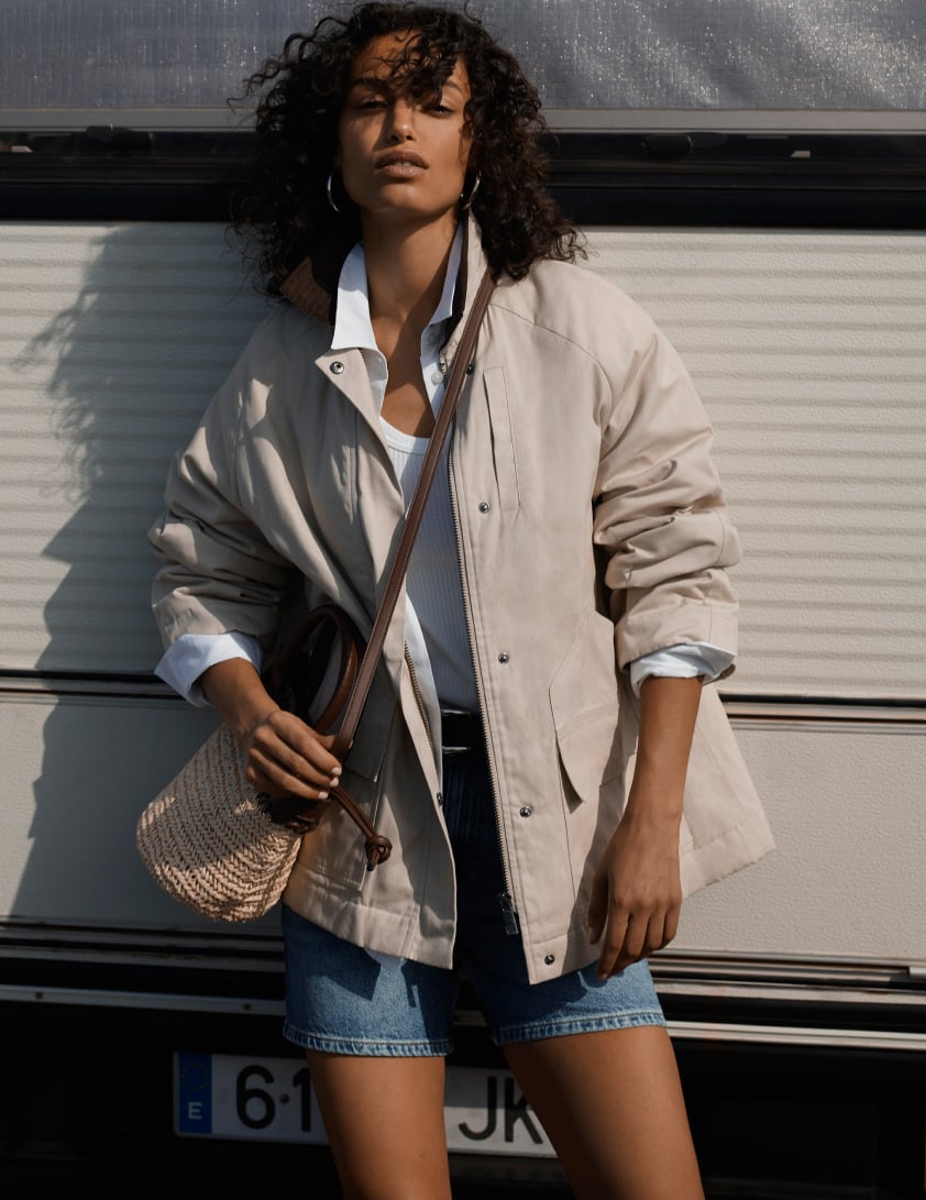 Woman wearing Whistles grey military style buttoned cardigan with black leather shorts