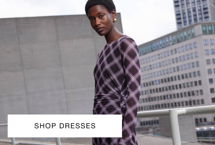 Woman wearing Whistles' purple checked long-sleeve maxi dress with gold earrings