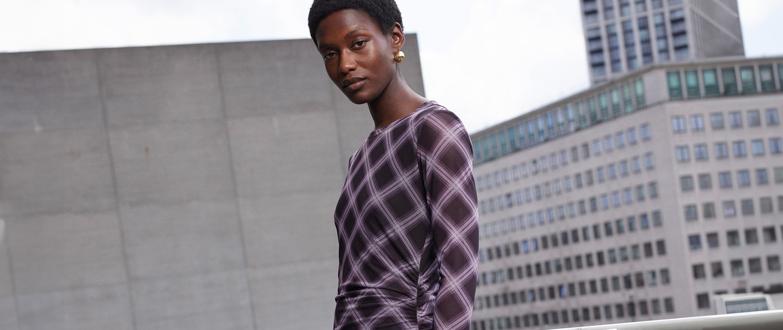 Woman wearing Whistles purple checked long sleeve maxi dress with gold earrings now 20% off.