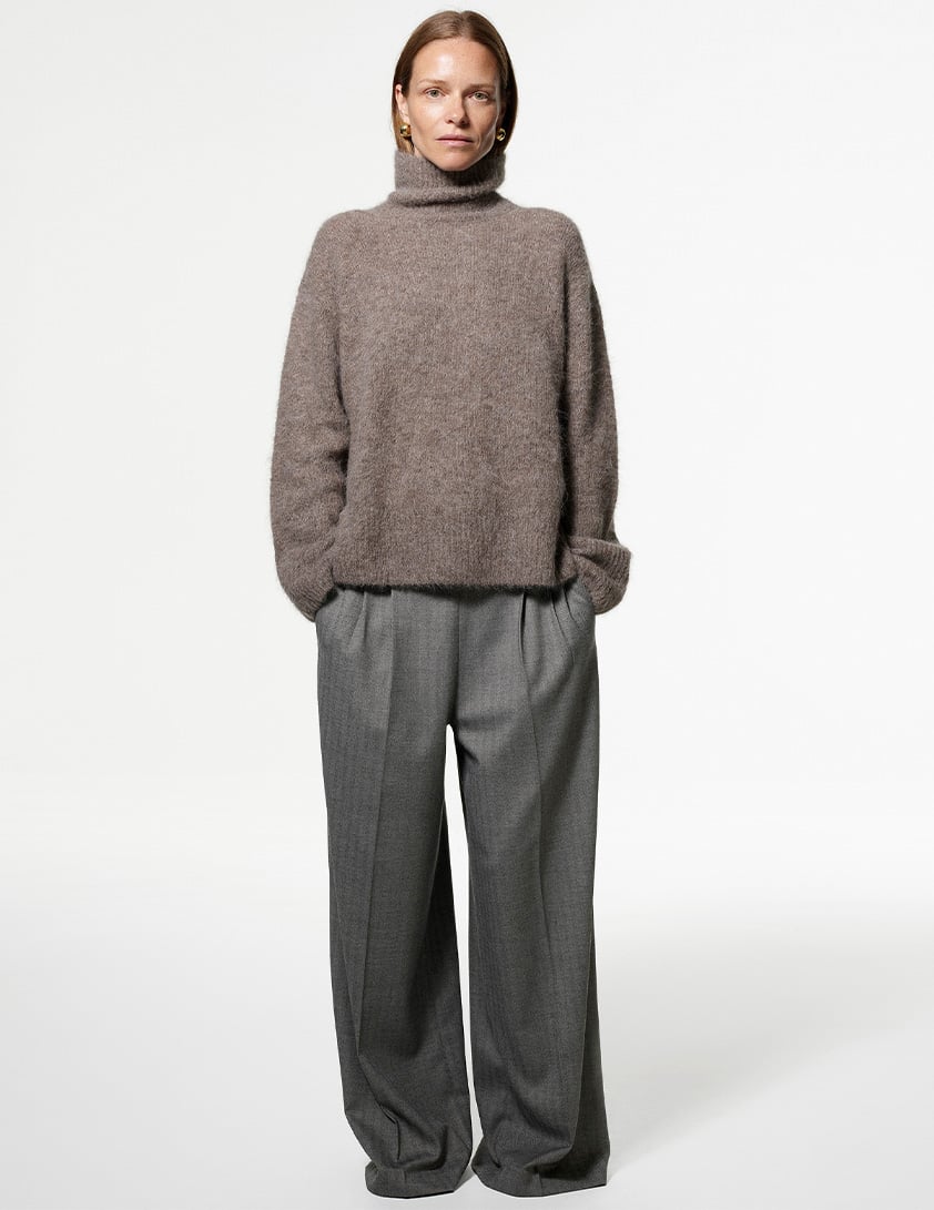 Woman wearing Whistles' brown roll-neck wool sweater and grey wide-leg tailored pleated trousers