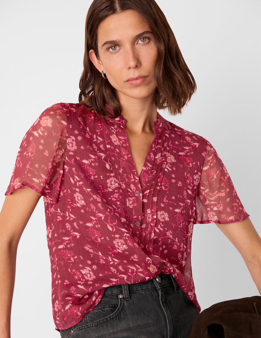 Woman wearing a short sleeve burgundy printed blouse for Whistles 15% percent off everything promotion