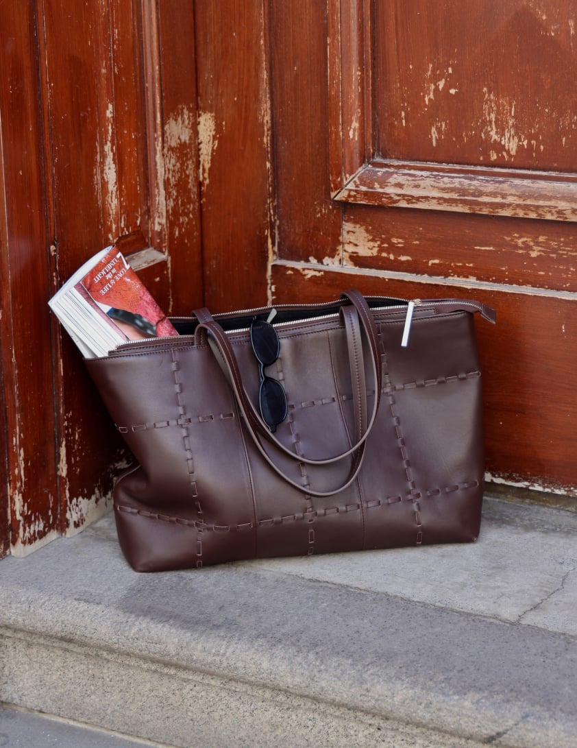 Model carrying a brown suede tote bag
