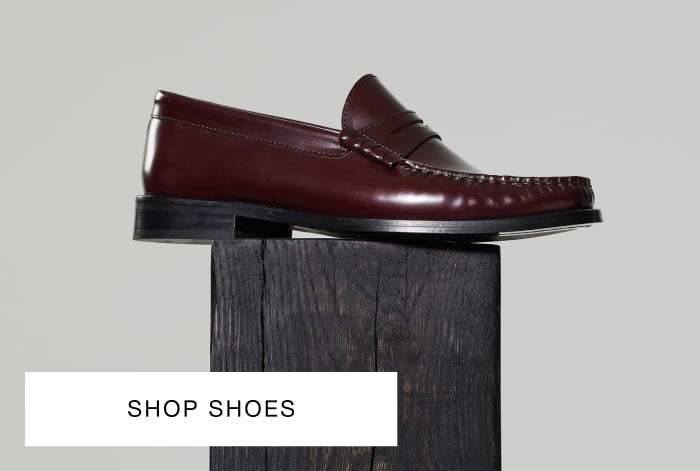 Whistles' burgundy slim leather loafer with a rounded toe, low heel and penny strap detail, placed on a dark wooden block