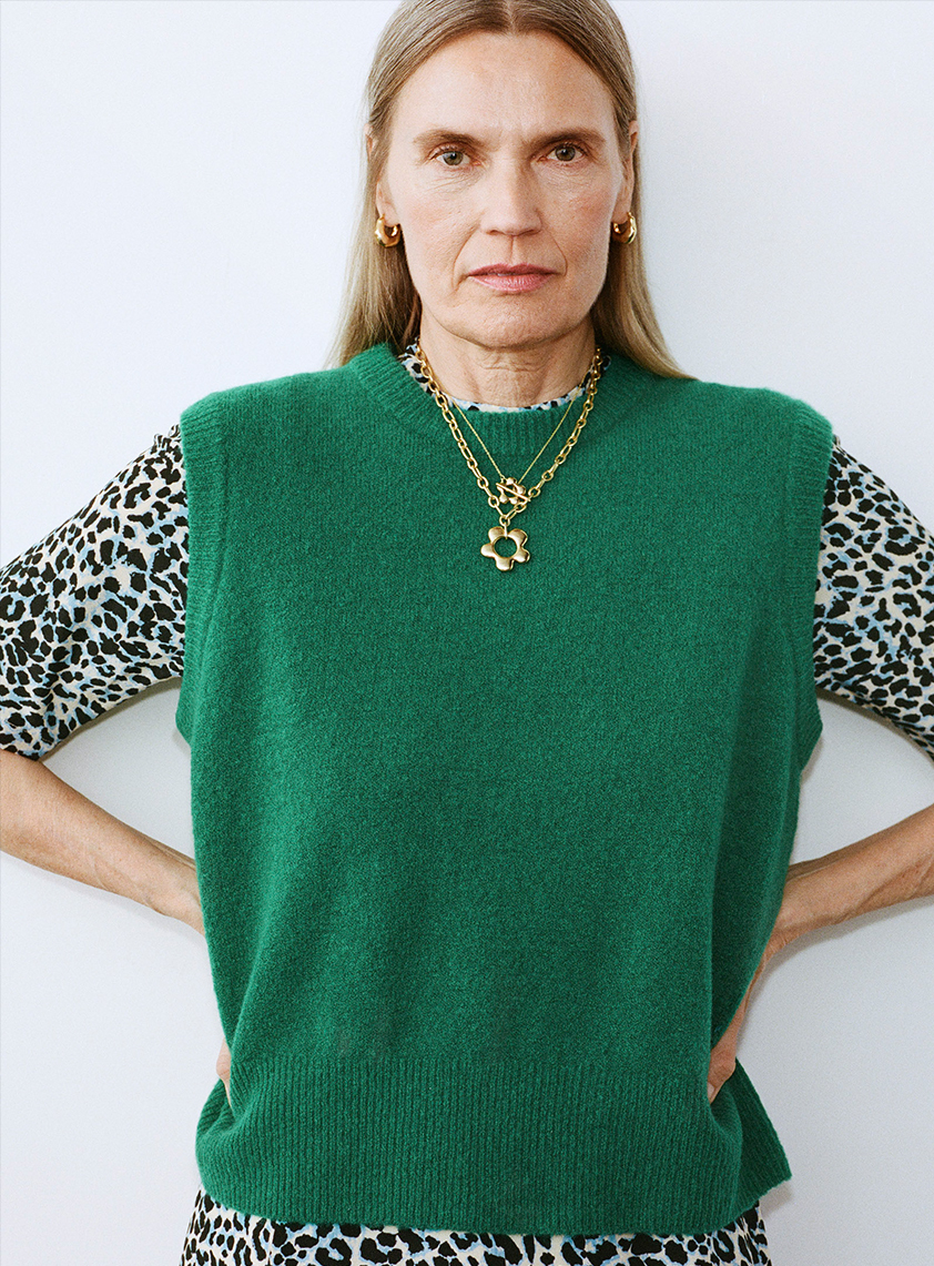 woman wearing a dress layered with a green sweater vest