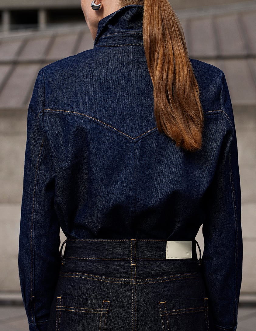 Woman wearing Whistles dark denim shirt tucked into dark denim jeans from behind